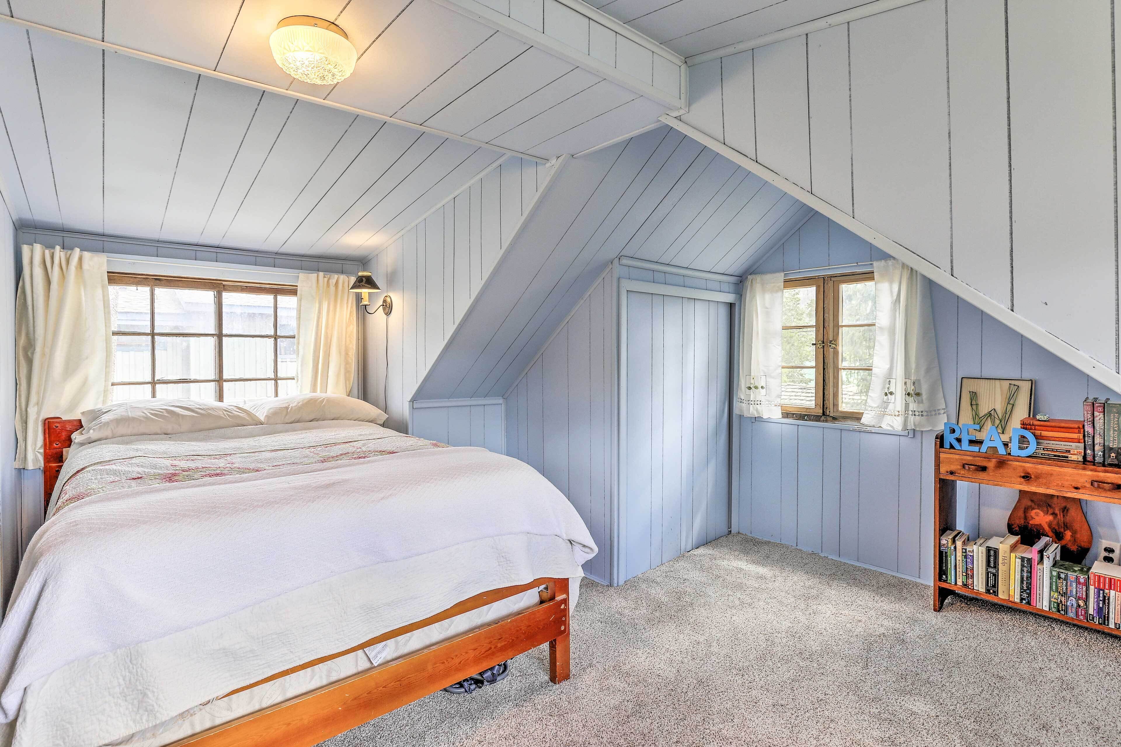 Une chambre à coucher avec un lit en bois, une bibliothèque et un plafond en pente.