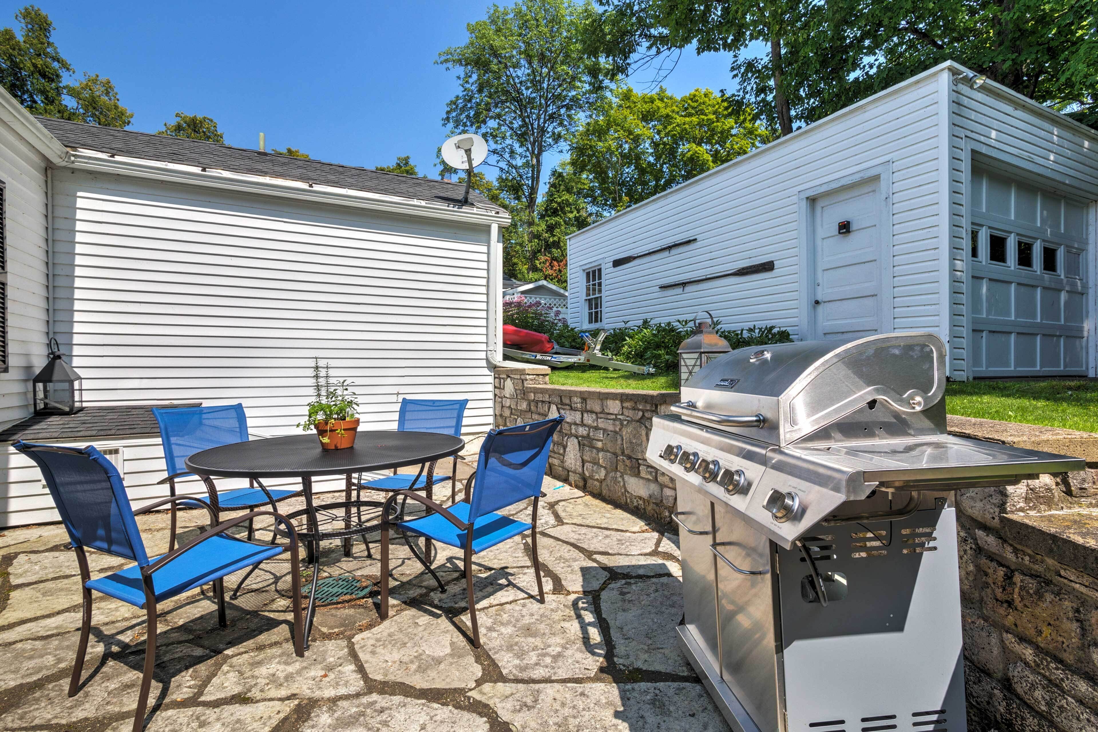Eine Terrasse im Freien mit Grill, blauen Stühlen und einem Tisch mit einem Blumentopf.