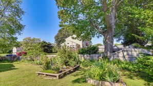 A residential property with a large tree, a well-maintained garden, and a wooden deck. - Bright Narragansett Beach Escape w/ Deck & Yard! (Narragansett)