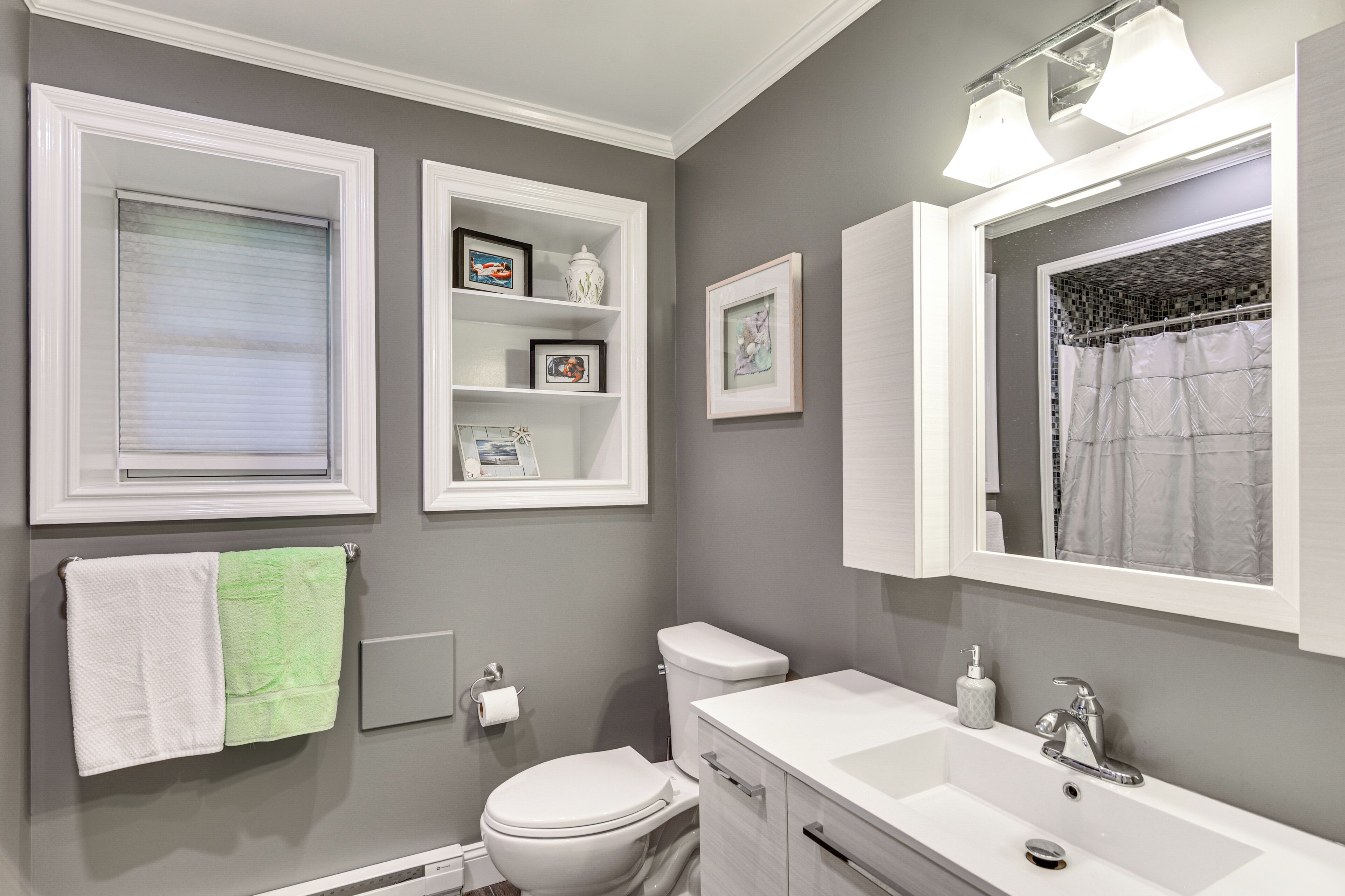 A bathroom with a toilet, sink, and a window with blinds.