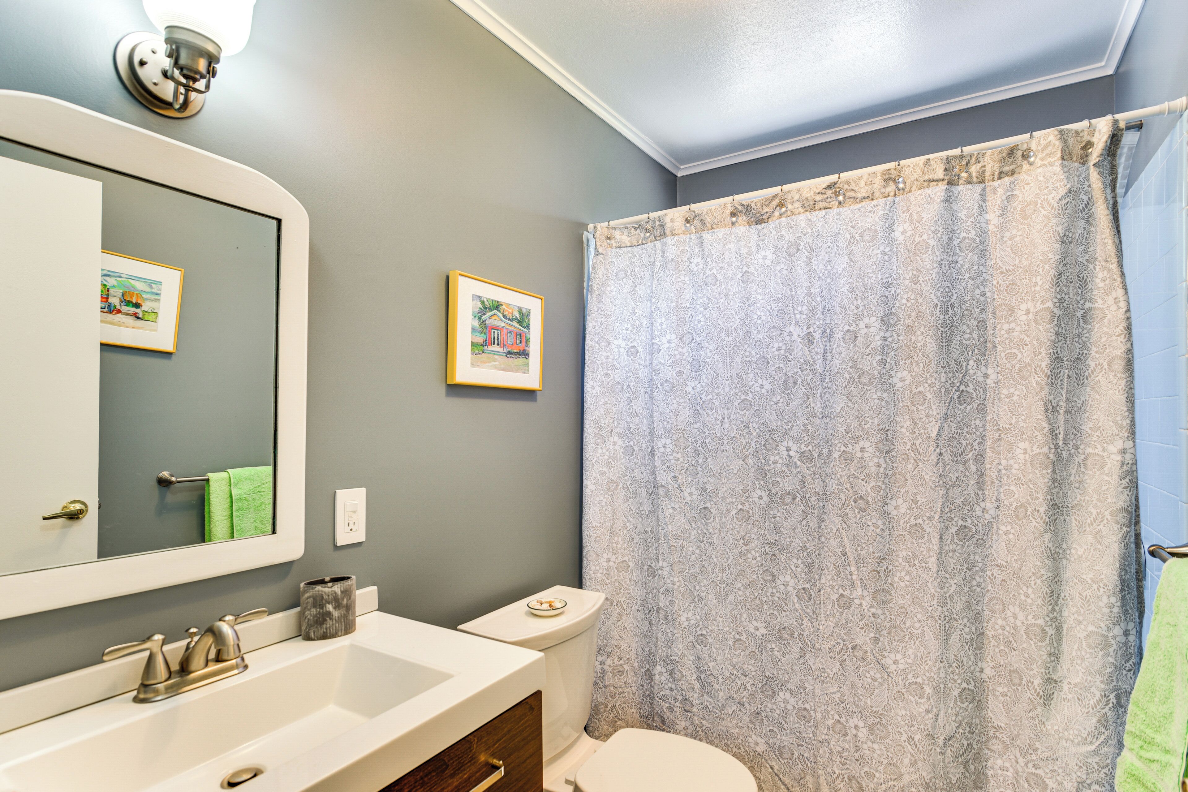 A bathroom with a white sink, a mirror, a toilet, and a shower curtain.