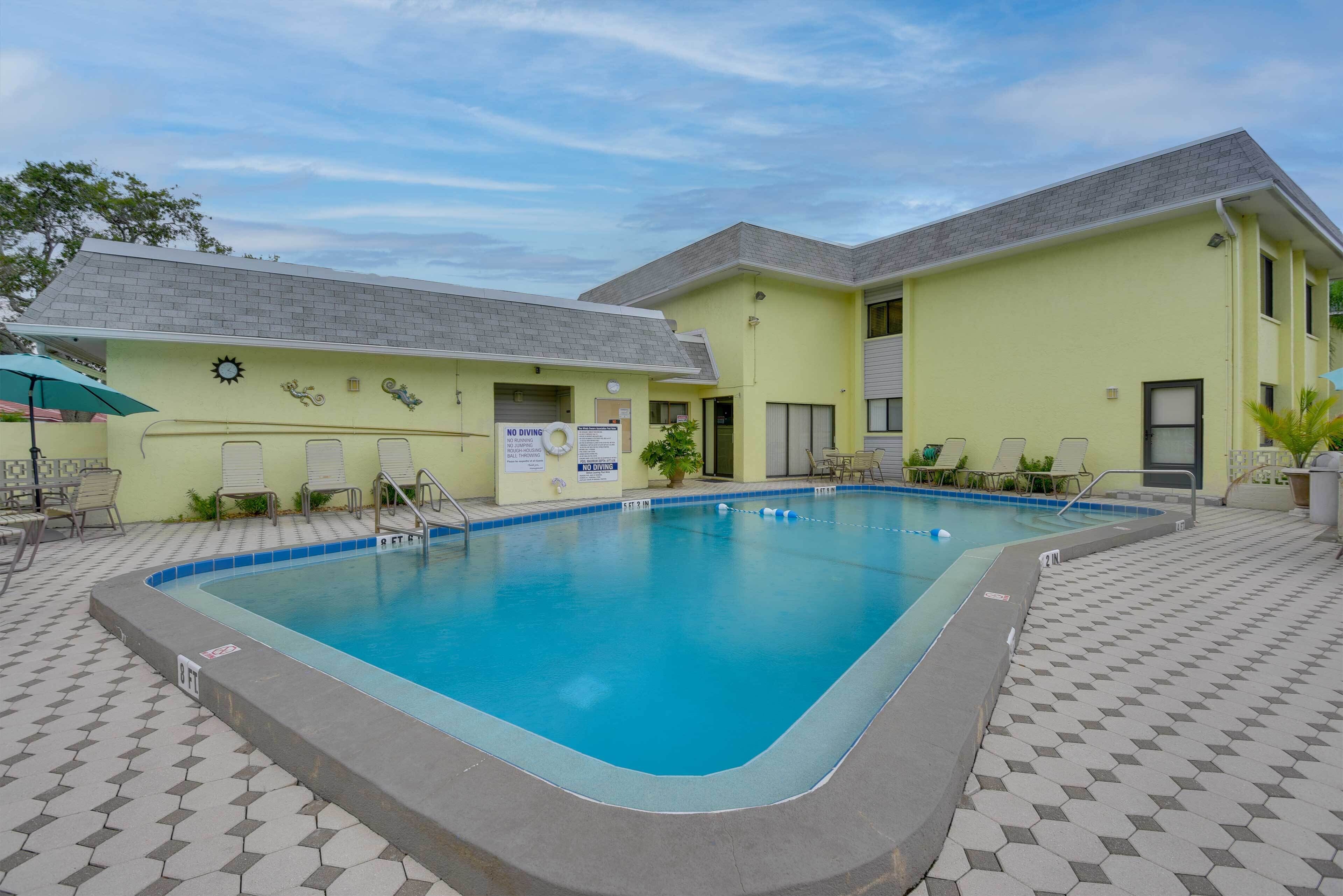 A swimming pool with a tiled deck, lounge chairs, and a 'No Diving' sign.