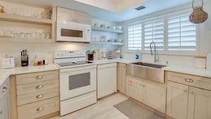 A modern kitchen with white cabinetry, a built-in microwave, a stove, and a sink. - Siesta Key Condo w/ Heated Pool < 1 Mi to Beach (Siesta Key)