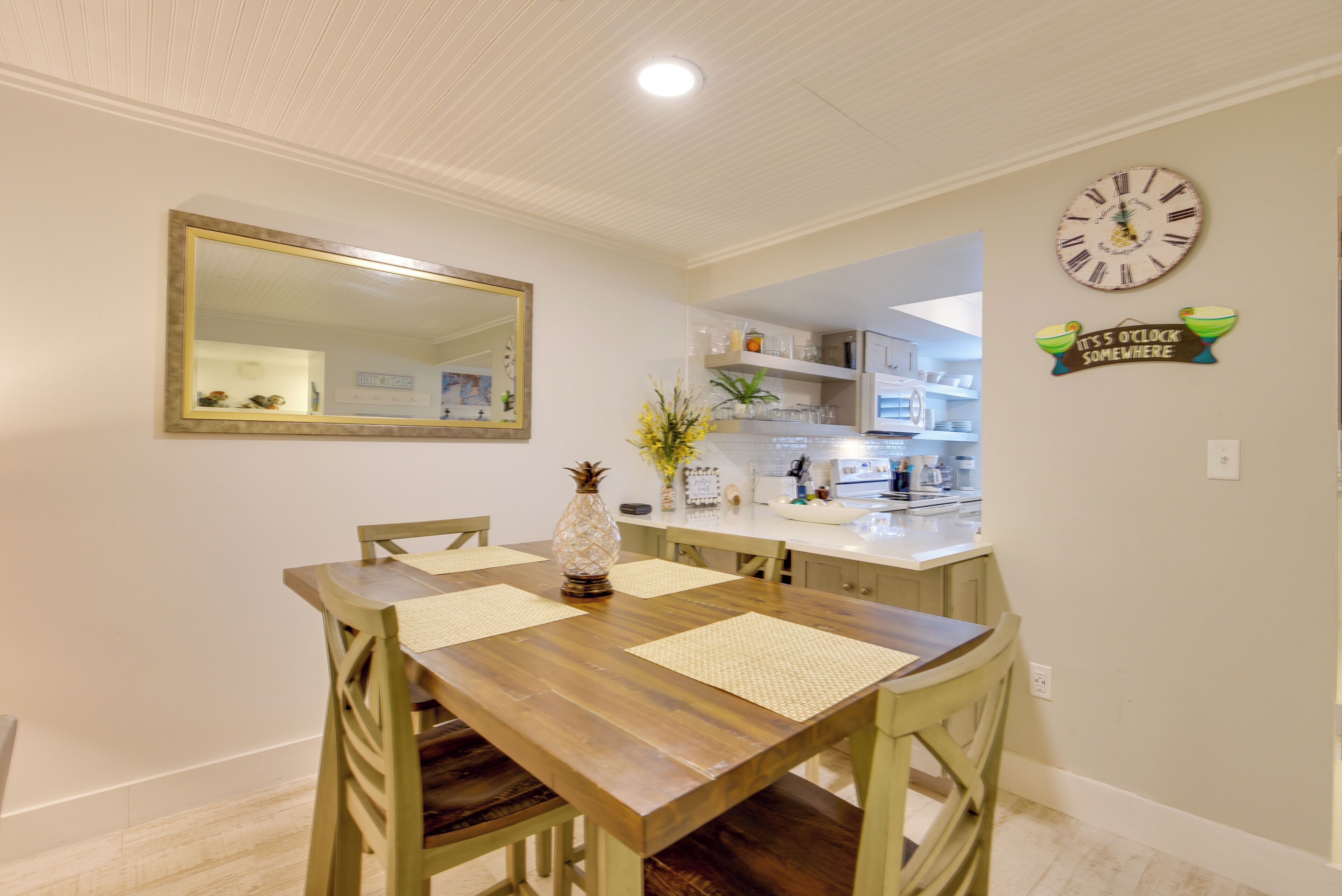 Un comedor con una mesa de madera, sillas y un espejo en la pared.