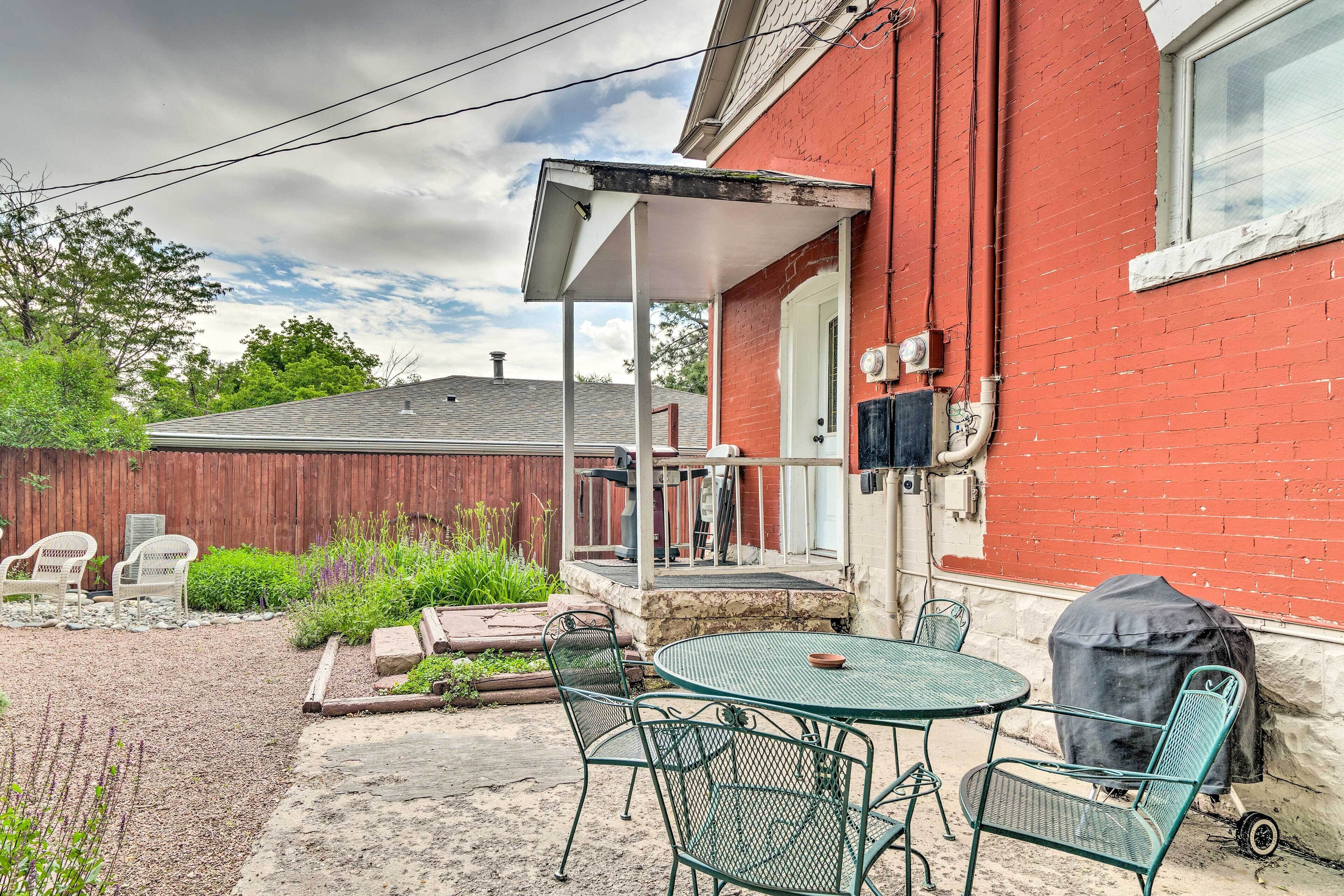 A patio with a table and chairs, a barbecue grill, and a covered outdoor seating area.