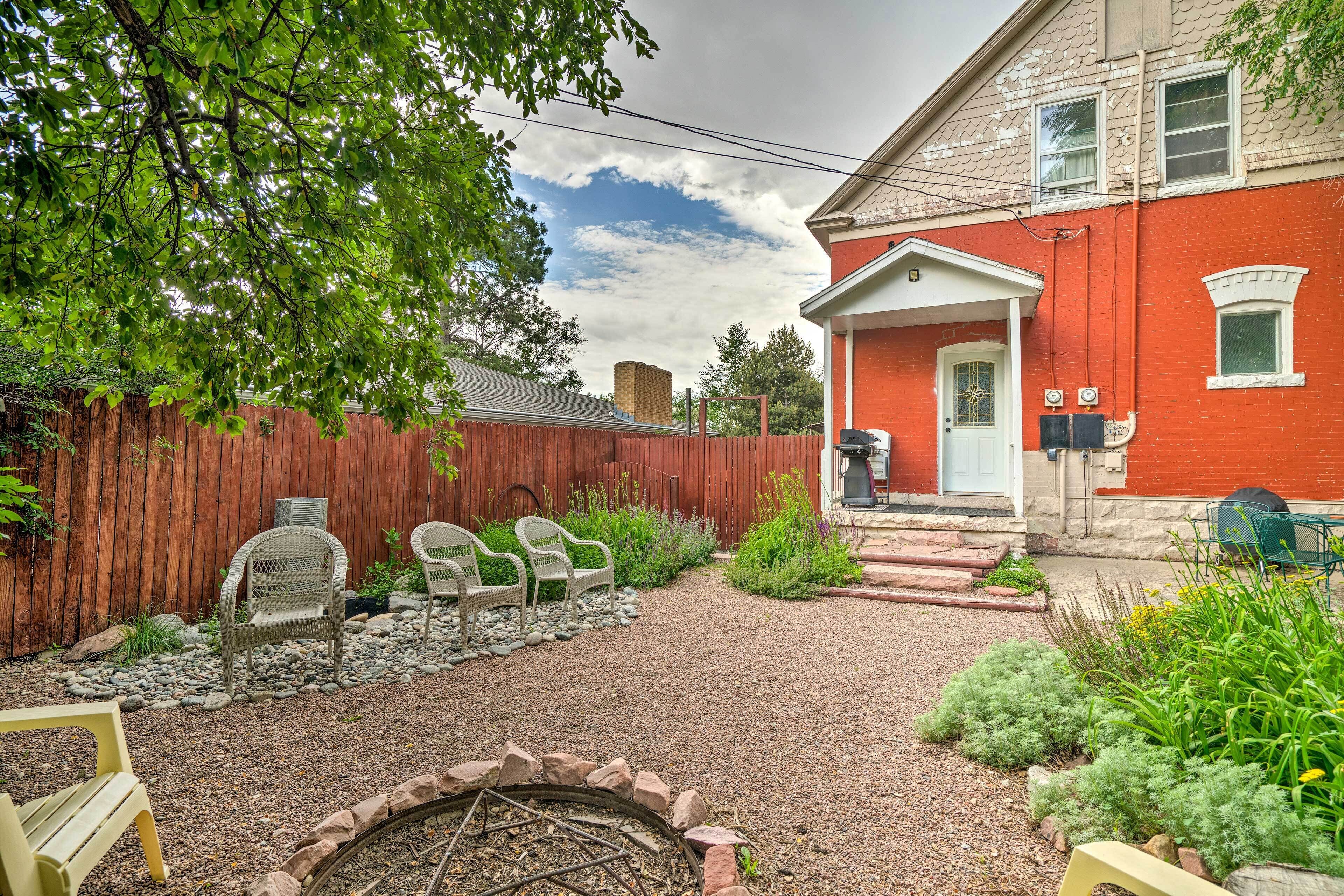 A backyard with a gravel path, a fire pit, and a red house with a white door.