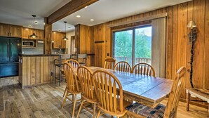 A wooden interior with a dining table and chairs, a kitchen area, and a large window. - 'peaceful Pines' Estes Park Home: Longs Peak View (Estes Park)