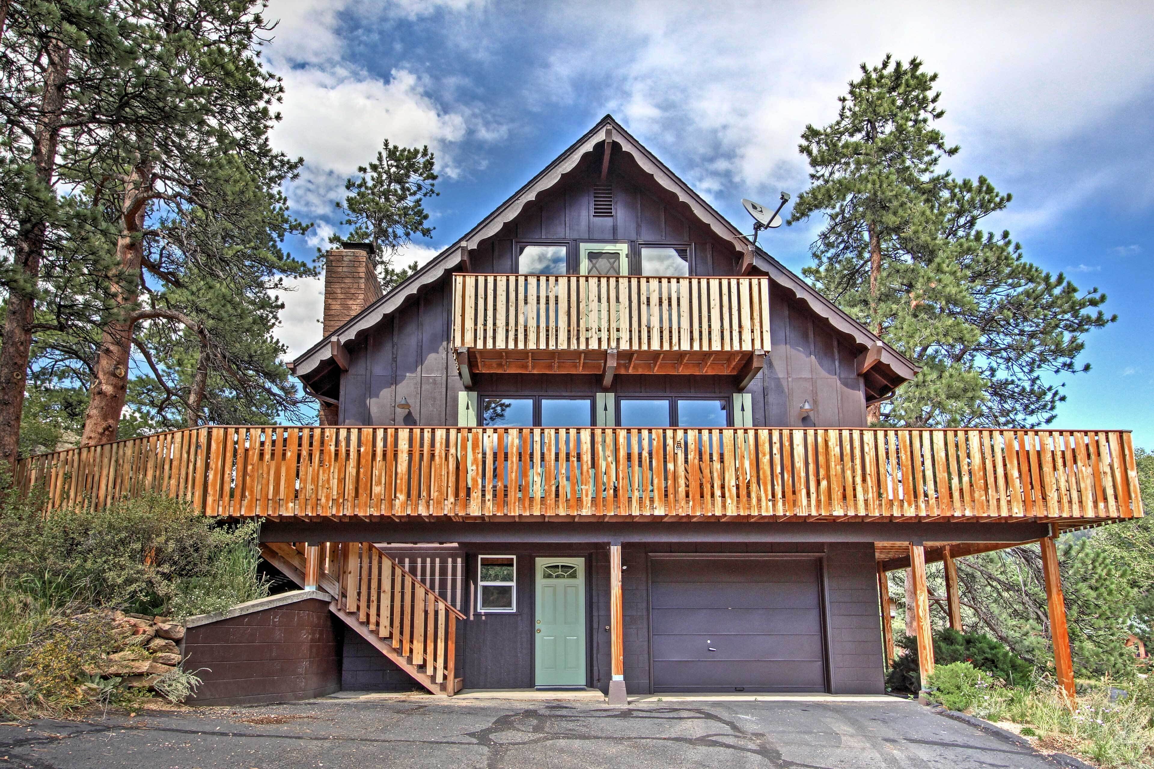 A two-story cabin with a wooden balcony, a garage, and a staircase leading to the entrance.