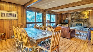 A wooden interior with a dining table, chairs, a sofa, and a stone fireplace. - 'peaceful Pines' Estes Park Home: Longs Peak View (Estes Park)