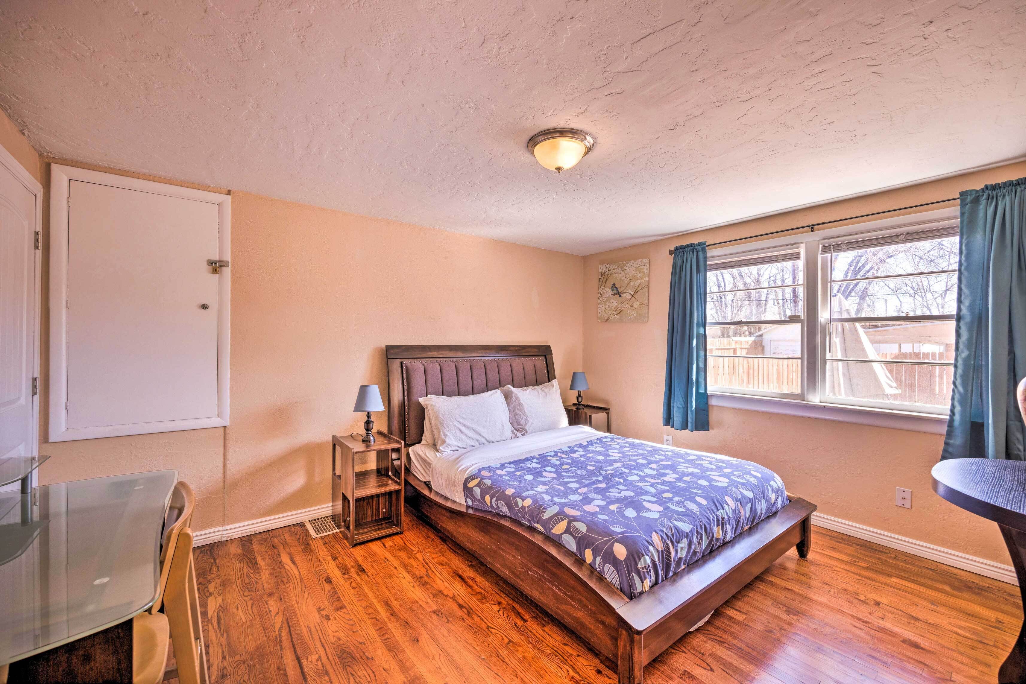 A bedroom with a wooden bed, a desk, and a window with curtains.