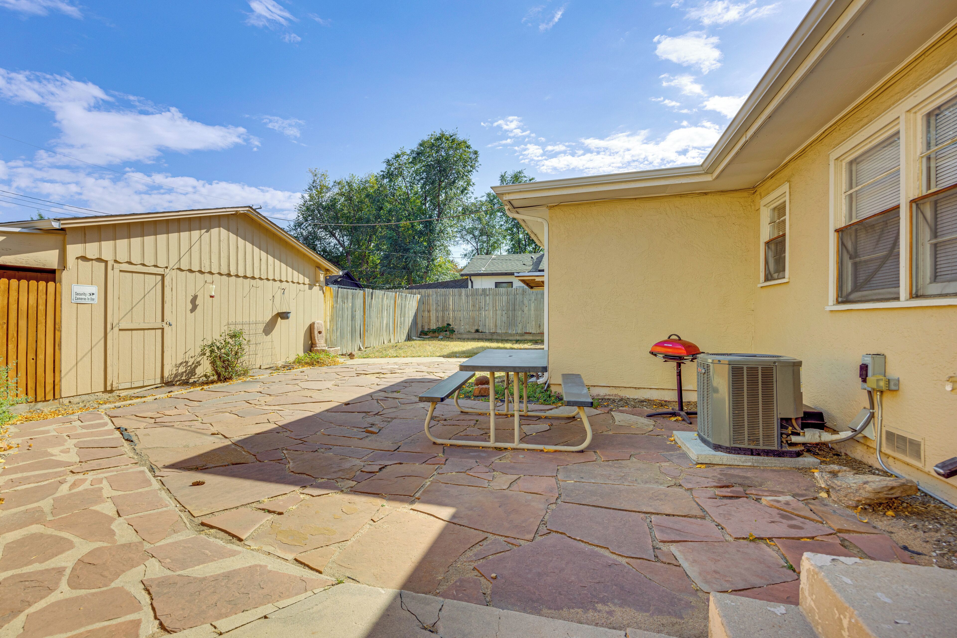 A patio with stone flooring, a picnic table, and an air conditioning unit.