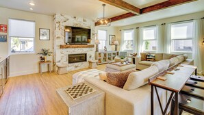 A spacious living room with a fireplace, a large sofa, a coffee table, and a TV mounted on the wall. - Stunning Home w/ Hot Tub Near Park City Skiing! (Park City)