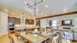 A spacious kitchen with a central island, wooden cabinets, and a modern chandelier. - Stunning Home w/ Hot Tub Near Park City Skiing! (Park City)