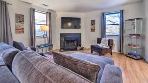 A living room with a fireplace, sofas, a TV, and a bookshelf.