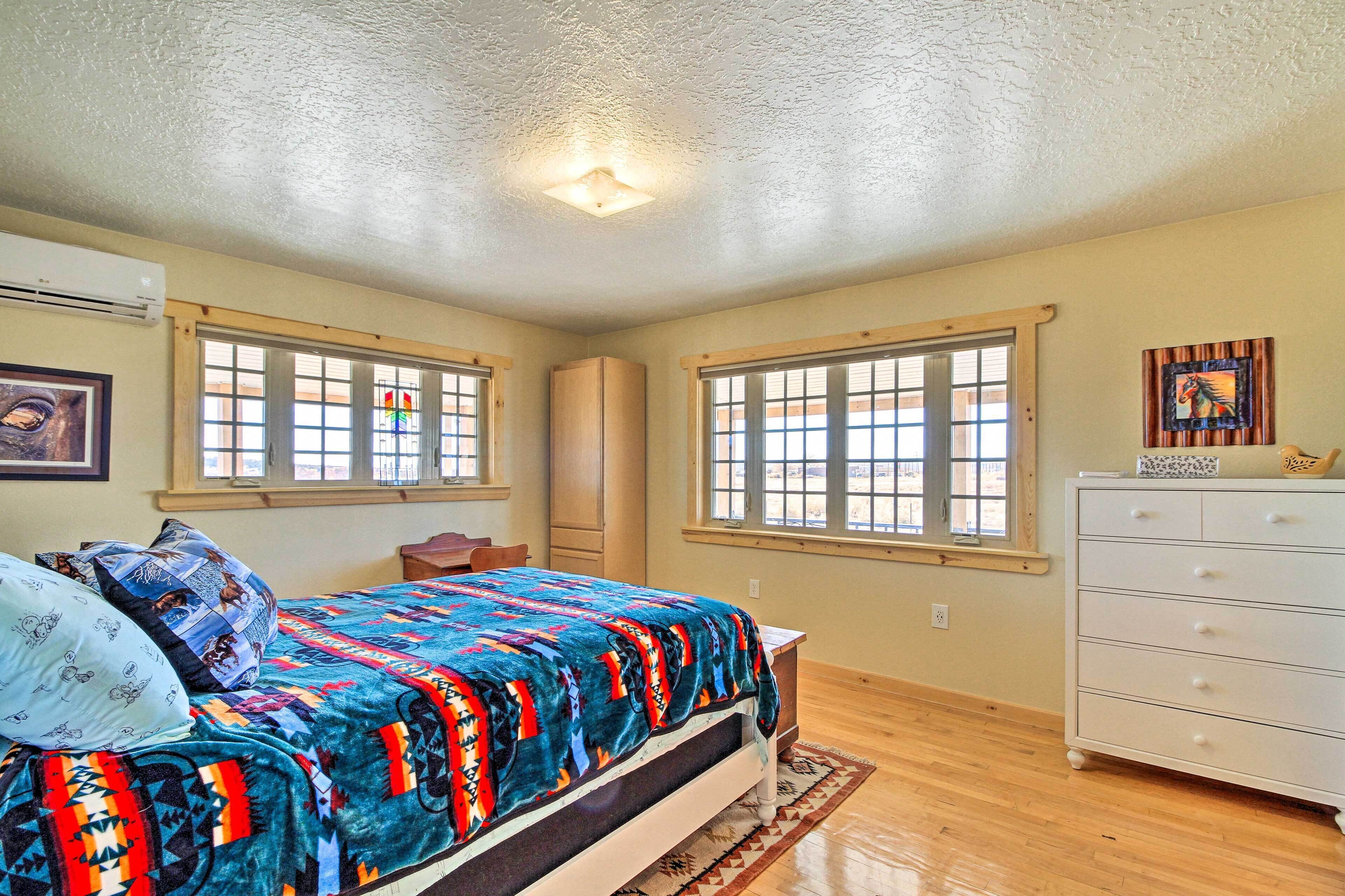 Une chambre à coucher avec un lit, une commode, des fenêtres et un luminaire au plafond.