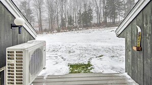 A view through a wooden door with a snow-covered yard and a large air conditioning unit on the left. - Near Newfound Lake: Plymouth Condo w/ Fireplace! (Plymouth)
