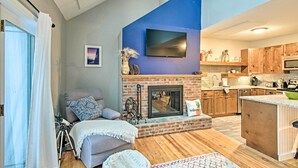 A modern living room with a fireplace, a television mounted on the wall, and wooden flooring. - Near Newfound Lake: Plymouth Condo w/ Fireplace! (Plymouth)