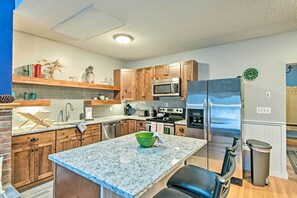 Una cocina moderna con encimeras de granito, electrodomésticos de acero inoxidable, armarios de madera y un salpicadero empotrado de ladrillo.