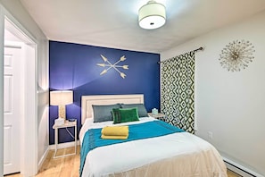 Un dormitorio con cama, mesita de noche, lámpara y decoración en la pared.
