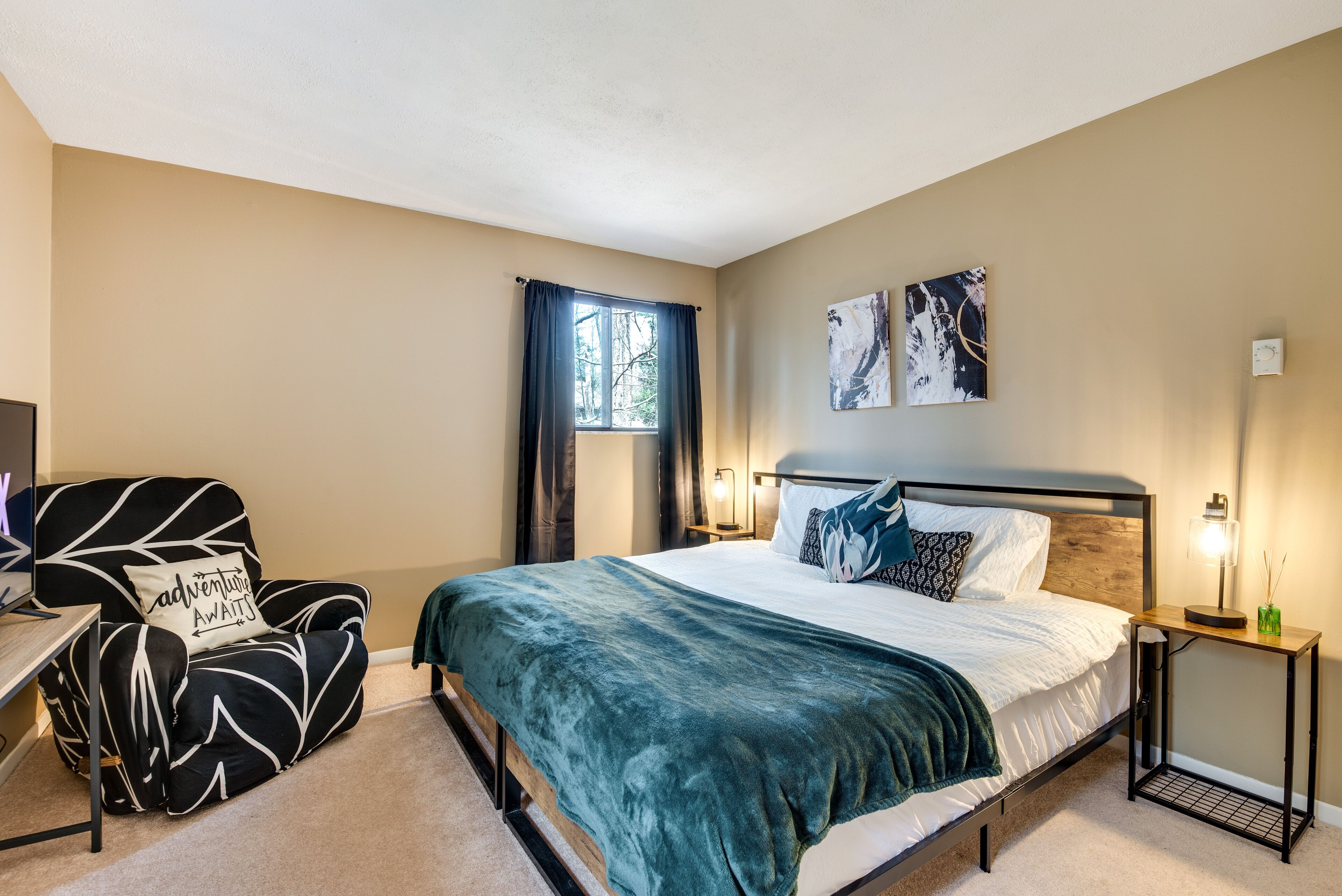 A bedroom with a bed, a chair, a desk, and two wall-mounted lamps.