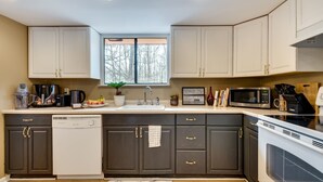 Une cuisine avec des meubles de couleur sombre, un lave-vaisselle, un four à micro-ondes et une cuisinière.