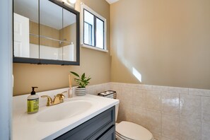 A bathroom with a white sink, gold faucets, a mirror, a potted plant, and a toilet. - Serene Pocono Pines Home: 2 Mi to Lake Naomi Beach (Pocono Pines)
