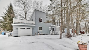 A two-story house with a garage, a covered porch, and a snow-covered yard.