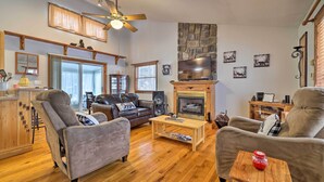 A spacious living room with a fireplace, leather sofas, a wooden coffee table, and a television.