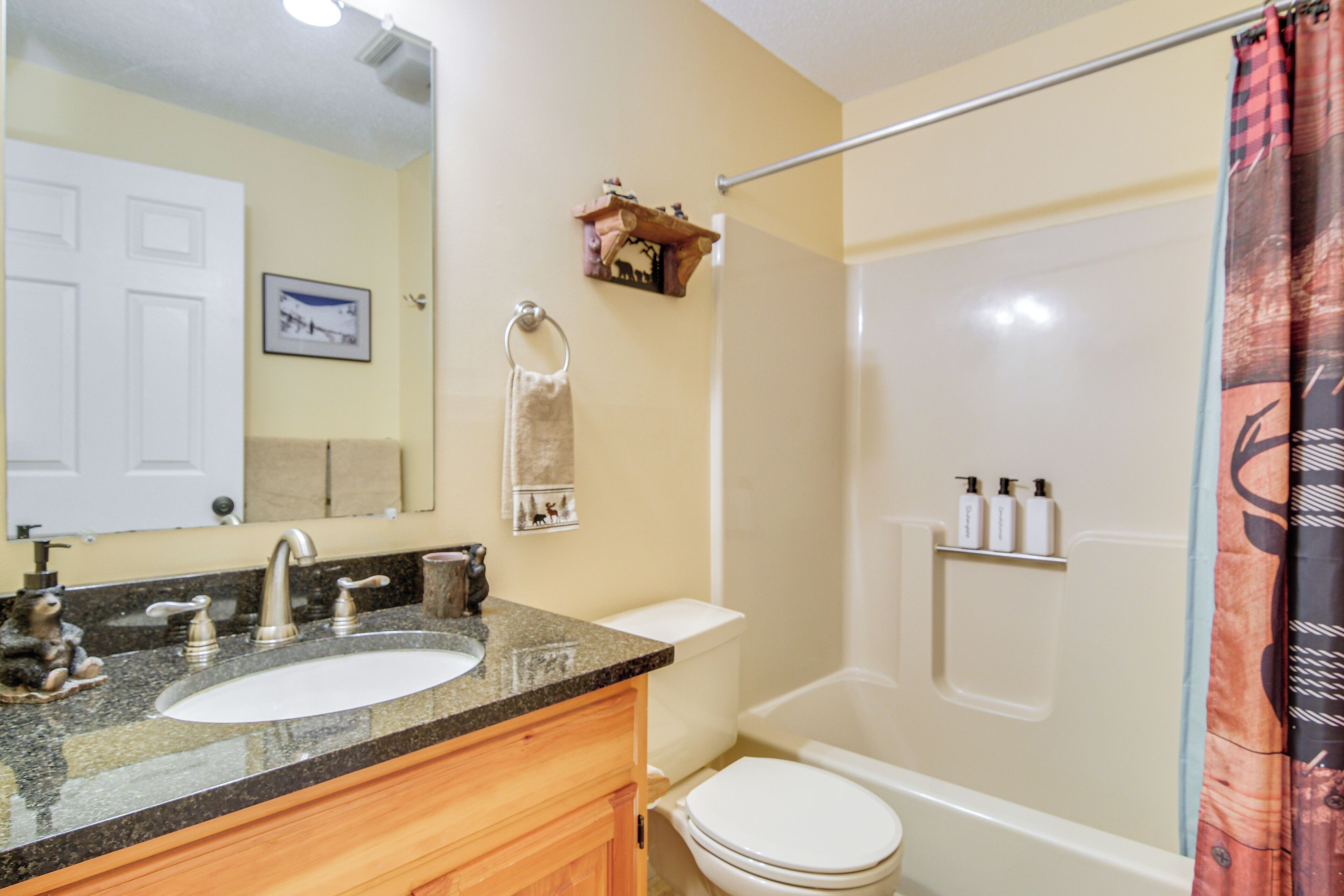 A bathroom with a sink, mirror, toilet, and shower.