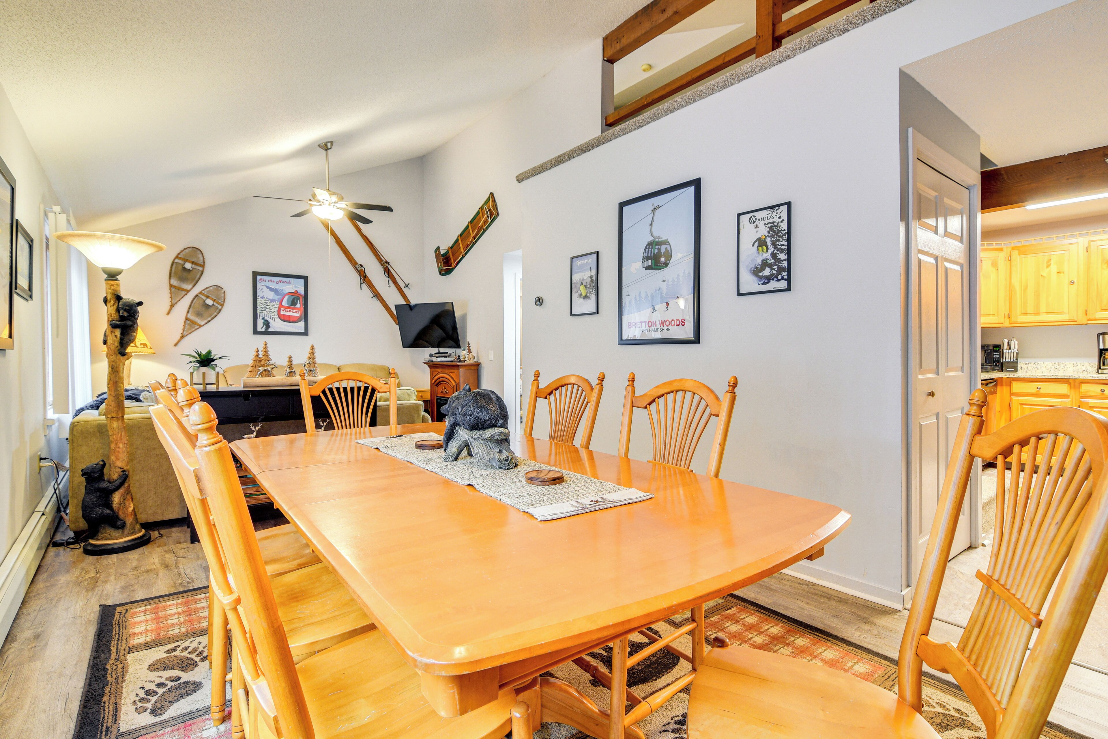 A dining area with a wooden table and chairs, a ceiling fan, and wall-mounted decorations.