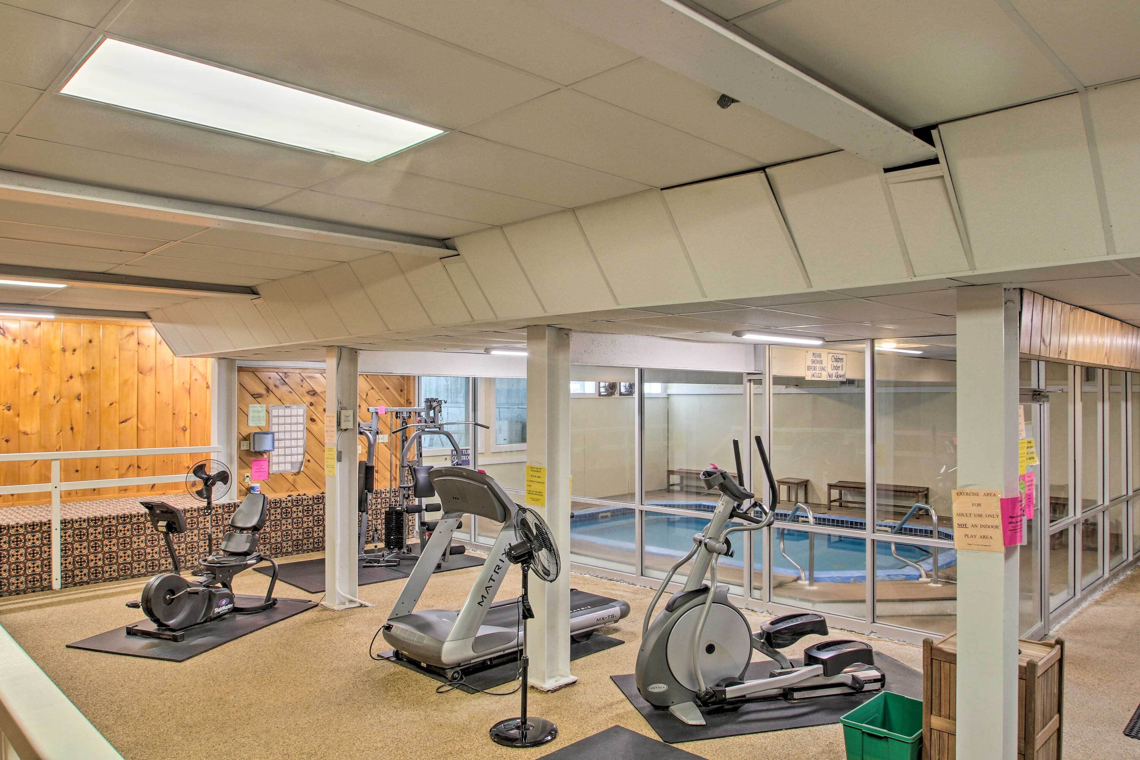A gym with exercise equipment, a pool, and wooden walls.