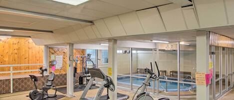 A gym with exercise equipment, a pool, and wooden walls.