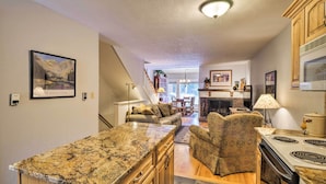 A kitchen with granite countertops, wooden cabinets, a built-in stove, and a dining area with a sofa and chairs.