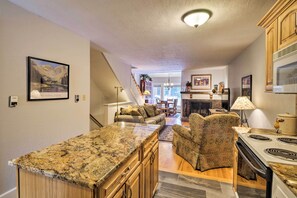A kitchen with granite countertops, wooden cabinets, a built-in stove, and a dining area with a sofa and chairs. - Ski-in/out Condo! Walk to Main Street Breckenridge (Breckenridge)