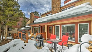 A covered outdoor patio with a barbecue grill, red chairs, and a glass table surrounded by snow. - Ski-in/out Condo! Walk to Main Street Breckenridge (Breckenridge)