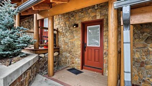 A stone exterior with a wooden porch, a red door, and a metal gutter. - Ski-in/out Condo! Walk to Main Street Breckenridge (Breckenridge)