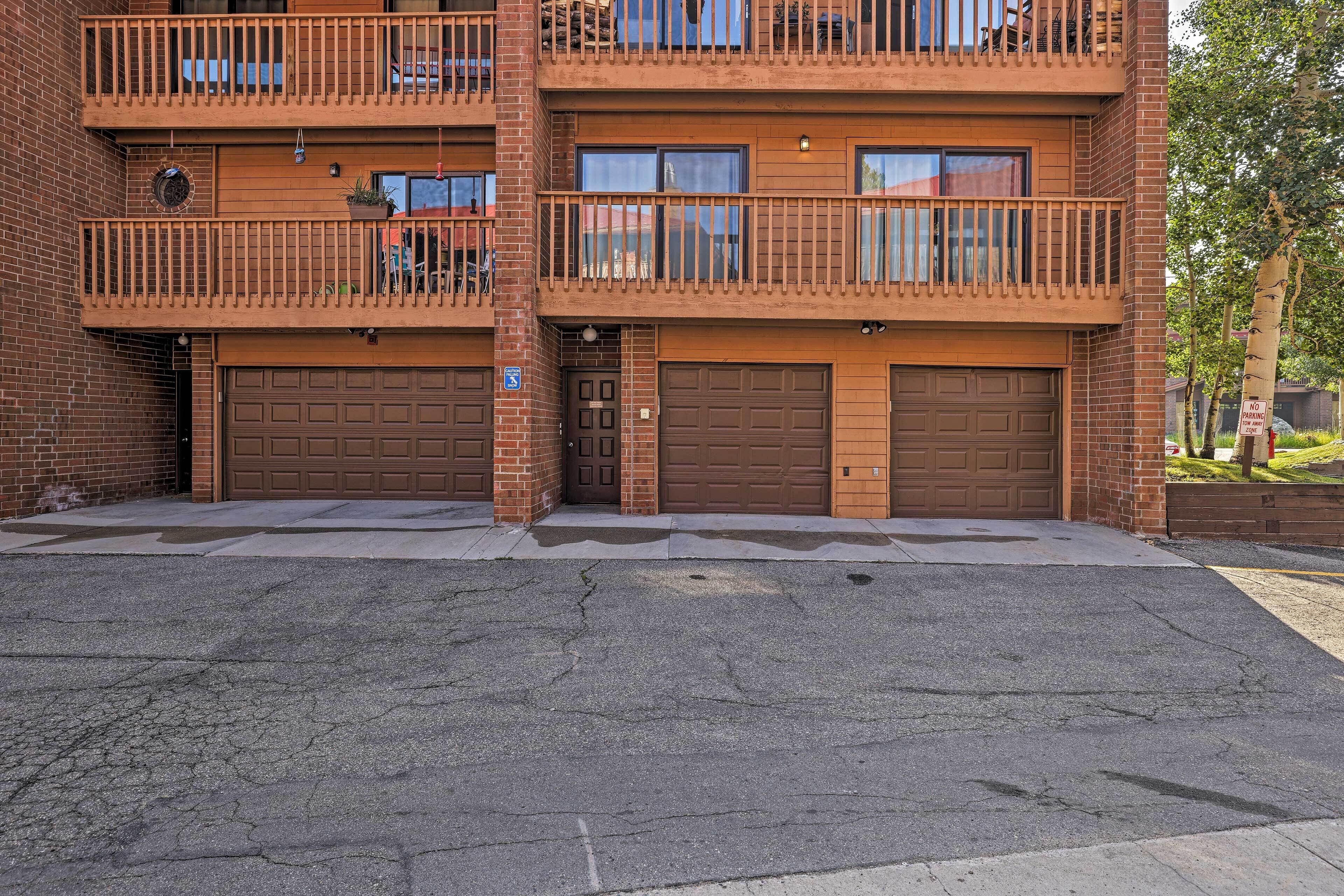 A multi-story brick building with two garages and a balcony on the second floor.
