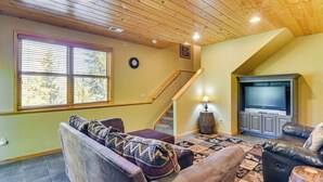A cozy living room with a wooden ceiling, a staircase, a television, and a patterned rug. - 1 Mi to Grand Lake: Family-friendly Gem w/ Hot Tub (Grand Lake)