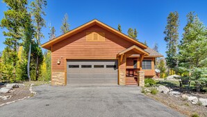 A two-story log cabin with a garage, surrounded by a forested landscape. - 1 Mi to Grand Lake: Family-friendly Gem w/ Hot Tub (Grand Lake)