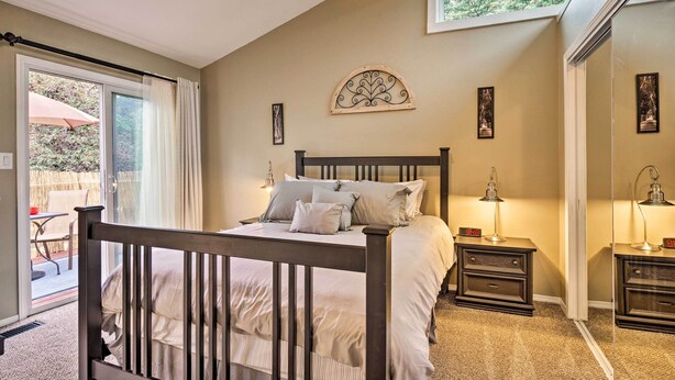 A bedroom with a bed, bedside tables, a window, and a view of the outdoors.