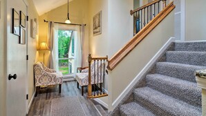 A staircase with a wooden handrail and carpeted steps leading to a door with a glass panel.