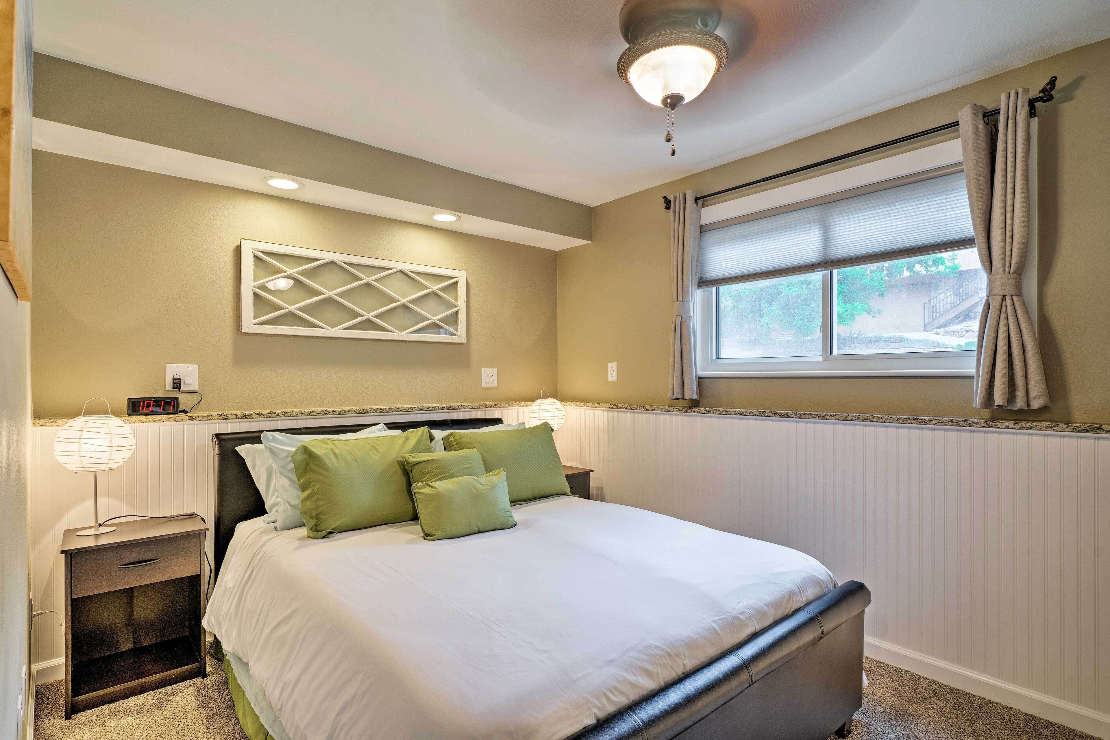 Une chambre à coucher bien rangée, avec un lit, une table de chevet, une lampe et une fenêtre avec des rideaux.