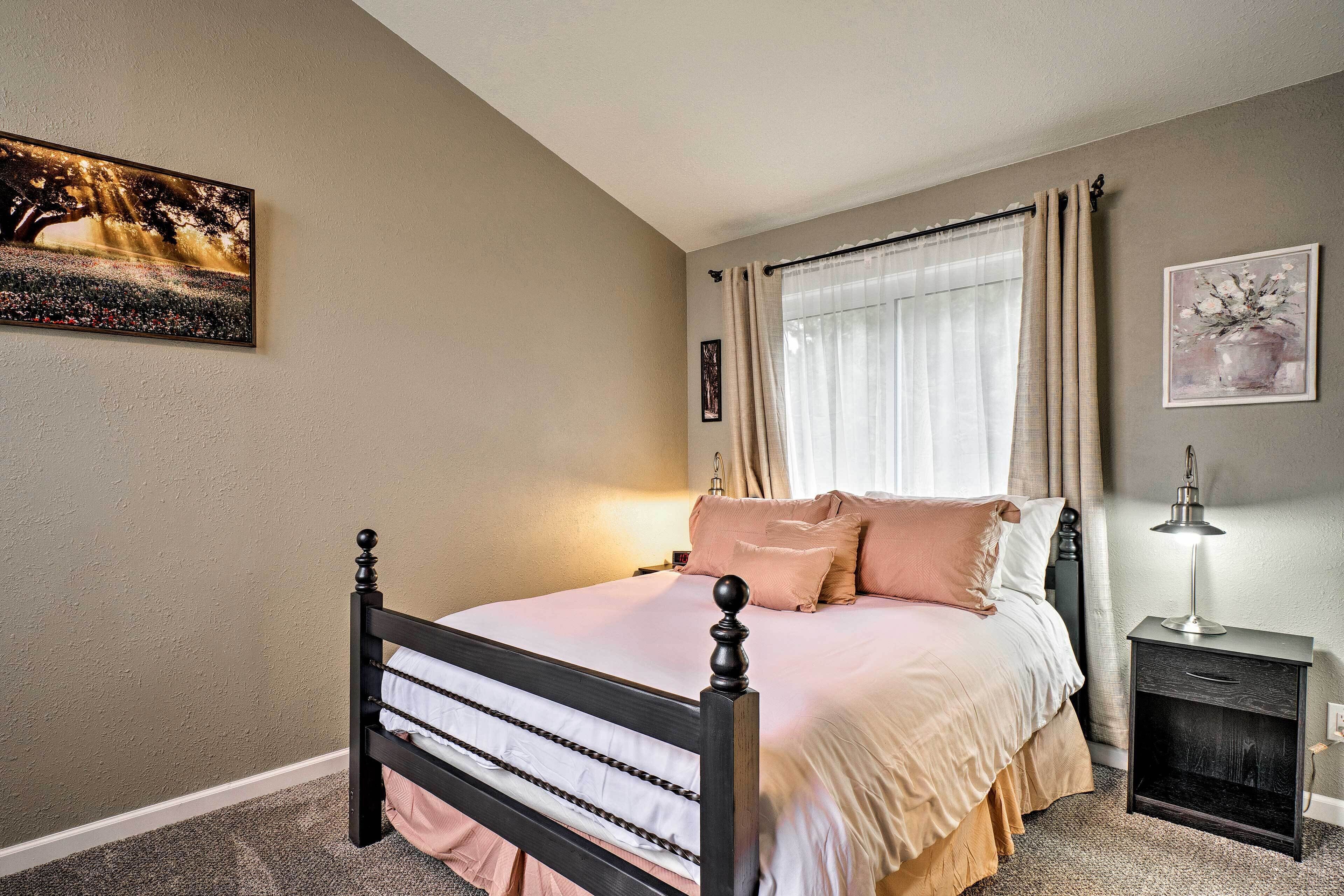A bedroom with a bed, a nightstand, a lamp, and artwork on the walls.