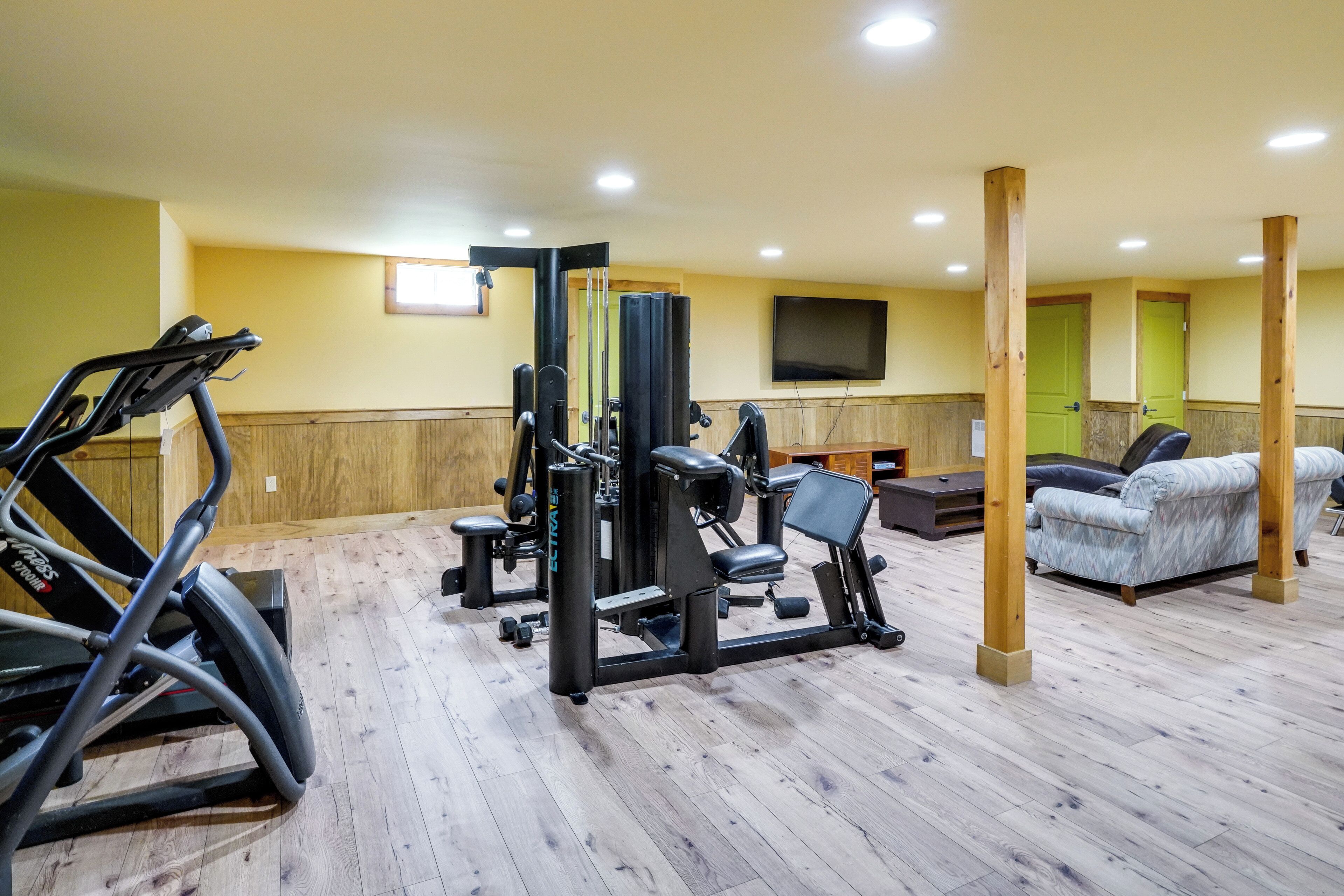 Ein Fitnessraum mit Trainingsgeräten, Laufband und einer Couch.