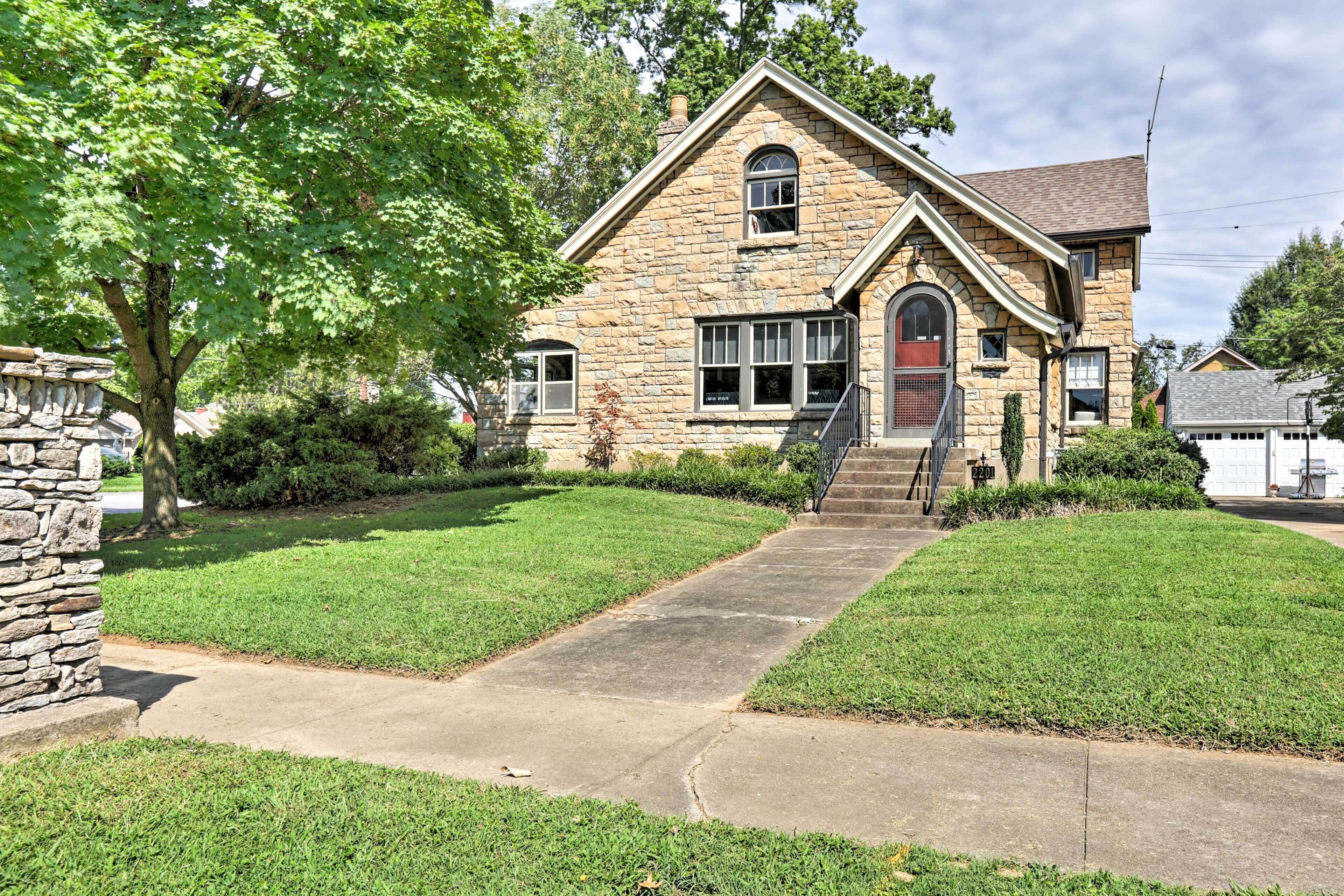 A stone house with a front entrance, a stone staircase, and a well-maintained lawn.