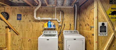 A laundry room with two washing machines, a dartboard, and a sign indicating a smoke-free zone.