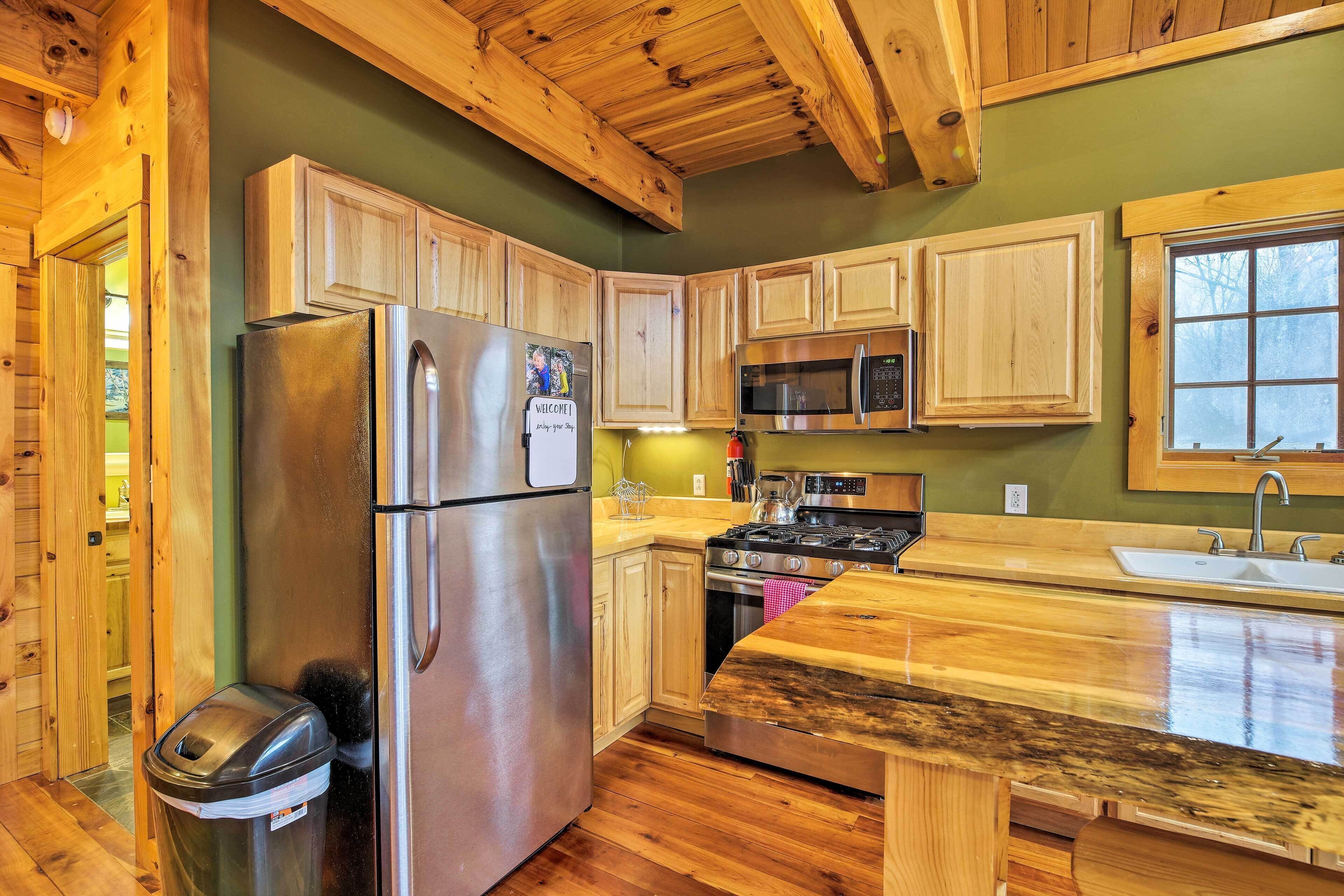 A kitchen with wooden cabinets, a stainless steel refrigerator, a microwave, a stove, and a sink.