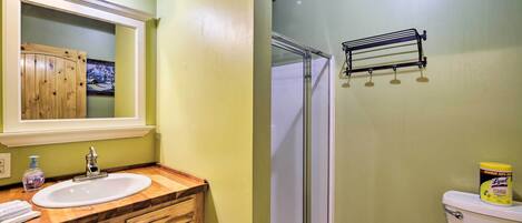 A bathroom with a wooden vanity, a sink, a mirror, and a toilet.