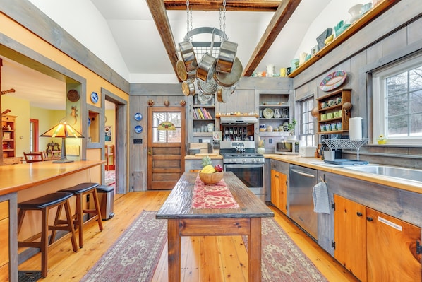 A kitchen with wooden countertops, a central island, and a hanging pot rack.