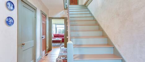 Un escalier avec une rampe en bois et un mur bleu clair.